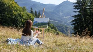 The best easels for painting 2023 for beginners and pros; a photo of a woman painting on a beach